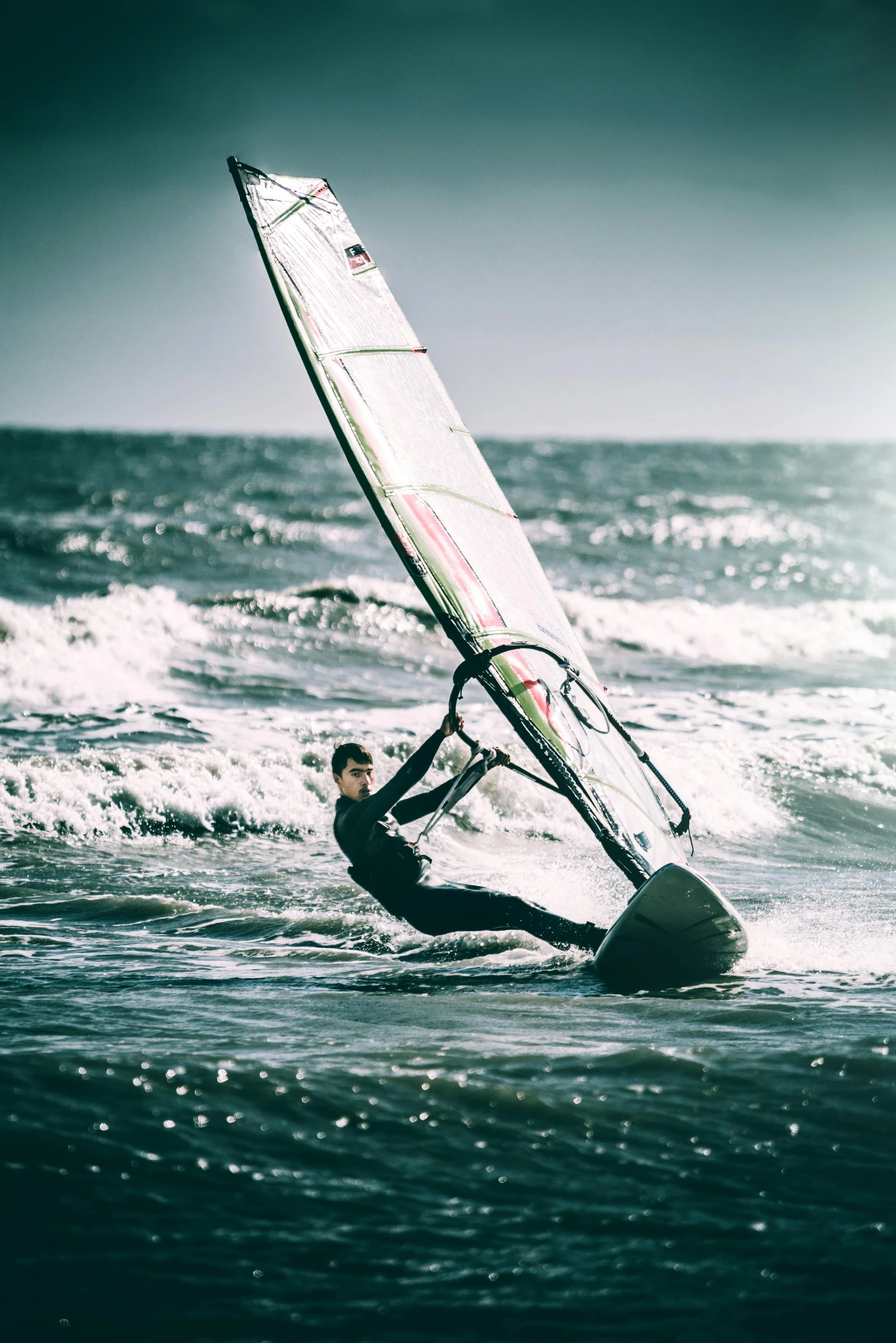 a person windsurfing in the ocean on a sunny day, by Matthias Stom, unsplash, grainy, mid fall, intense look, beaching