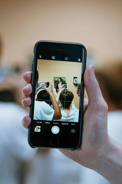 a person taking a picture with a cell phone, a picture, happening, center of image, schools, no cropping, in 2 0 1 8