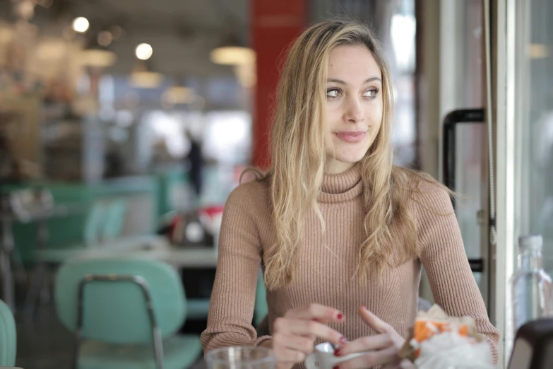 a woman sitting at a table with a plate of food, sydney sweeney, medium head to shoulder shot, unblur, brown