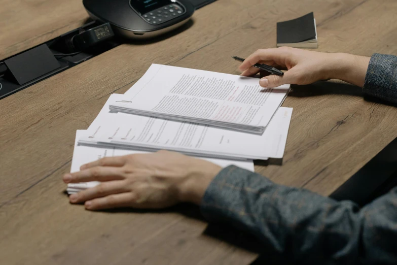 a person sitting at a desk with papers and a cell phone, by Carey Morris, pexels contest winner, royal commission, live-action archival footage, background image, ground level shot