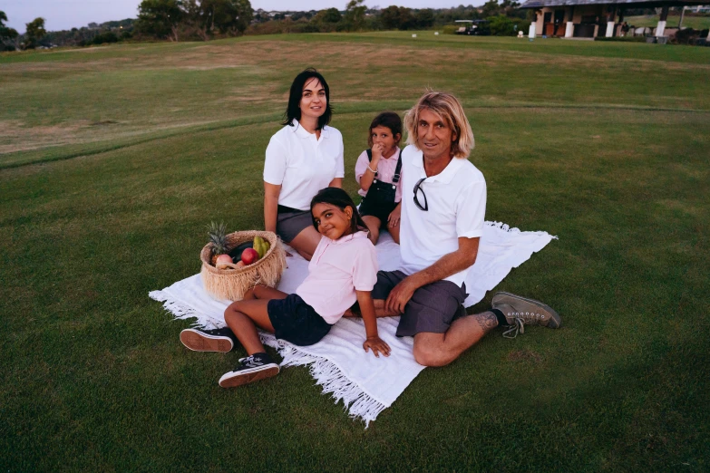 a group of people sitting on top of a grass covered field