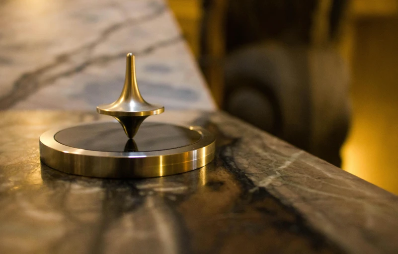 a close up of a metal object on a table, unsplash, kinetic art, levitating citadel, brass, on the altar, whirling