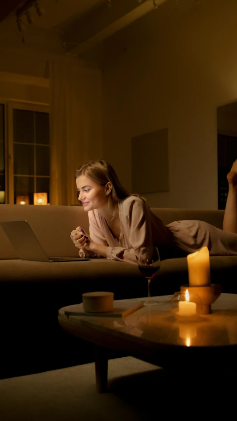 a woman laying on a couch next to a lit candle, trending on pexels, sitting in front of computer, connectivity, very romantic, high quality photo