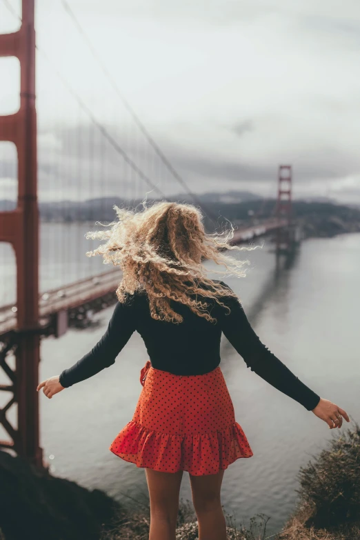 a woman standing in front of the golden gate bridge, pexels contest winner, renaissance, windy hair, a blond, spreading her wings, color photo