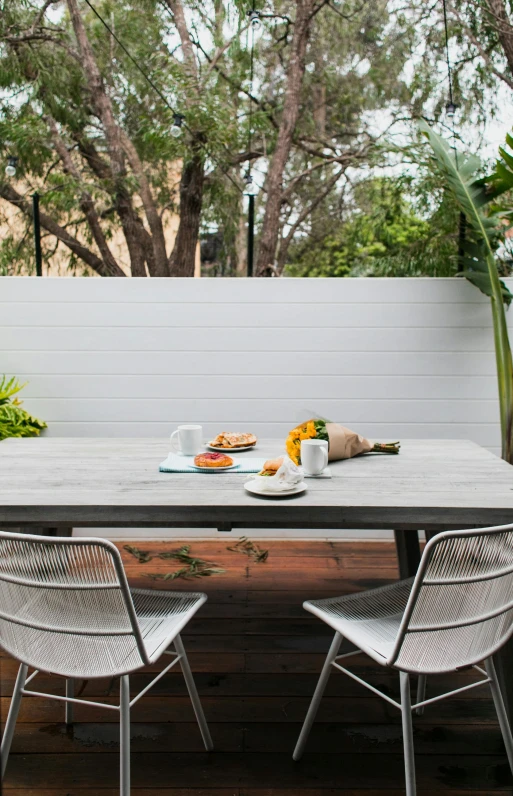 a wooden table sitting on top of a wooden deck, by Elizabeth Durack, minimalism, white block fence, breakfast, panorama shot, tropical vibe