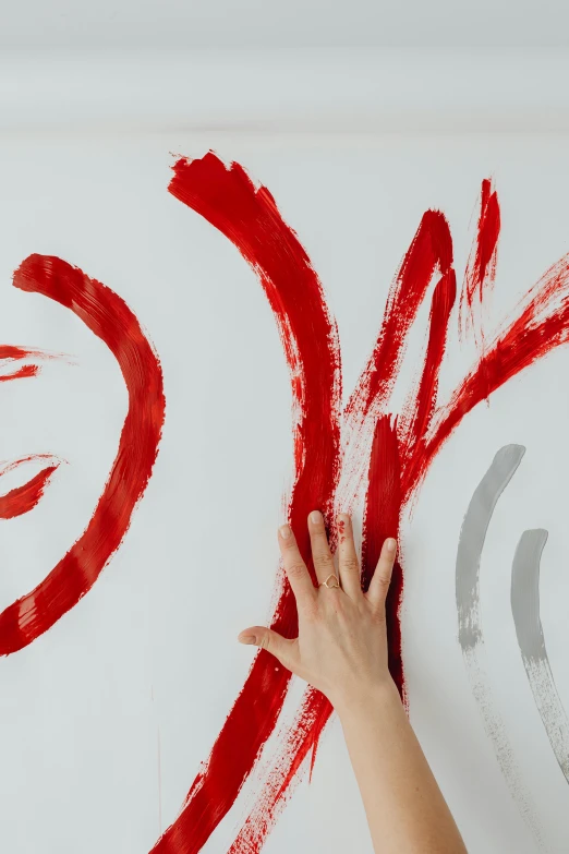 a woman is painting on a wall with red paint, an abstract drawing, inspired by Lucio Fontana, trending on pexels, action painting, enso, whiteboard, hands reaching for her, white red