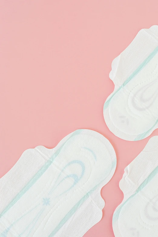 a pair of sanitary pads sitting on top of a pink surface, detailed product image, detail shot, 84mm), multi-part