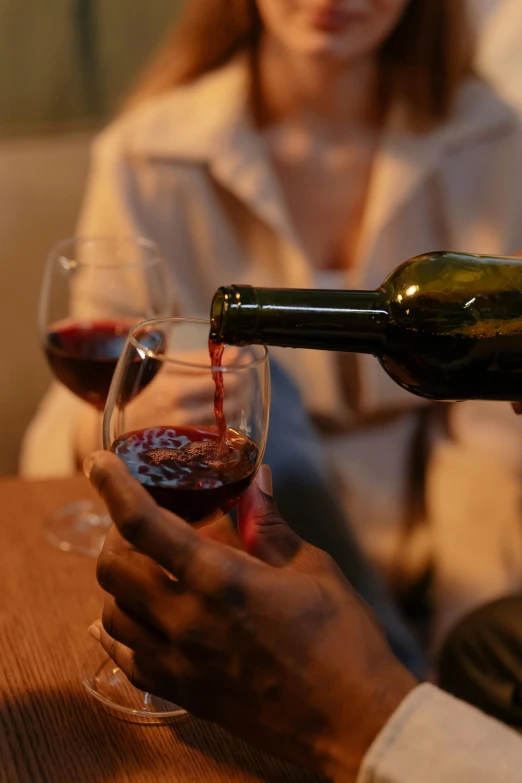 a man pours a glass of wine into a woman's hand, pexels contest winner, enhanced noise, low light, 4l, bl