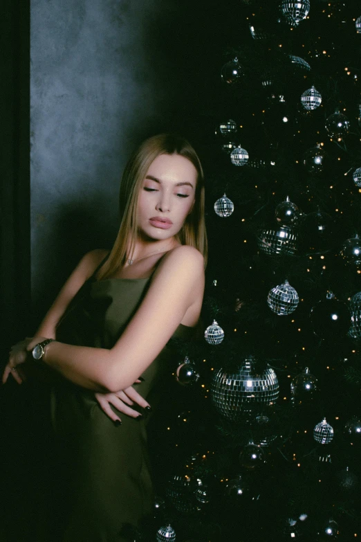 a woman posing in front of a christmas tree, an album cover, inspired by Elsa Bleda, pexels, realism, ukrainian girl, sleepy, sophisticated young woman, 15081959 21121991 01012000 4k