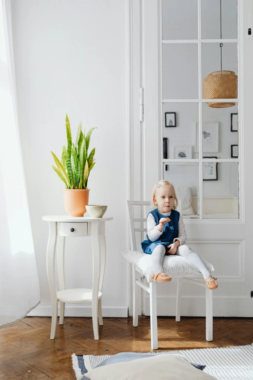 a little girl sitting on a chair in a room, inspired by Constantin Hansen, shutterstock contest winner, minimalism, large potted plant, white, toddler, front facing