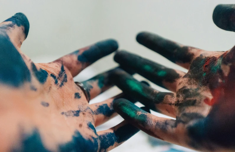 a close up of a person's hands covered in paint, a colorized photo, by Matija Jama, trending on pexels, black and teal paper, green and brown clothes, instagram post, dirt and unclean