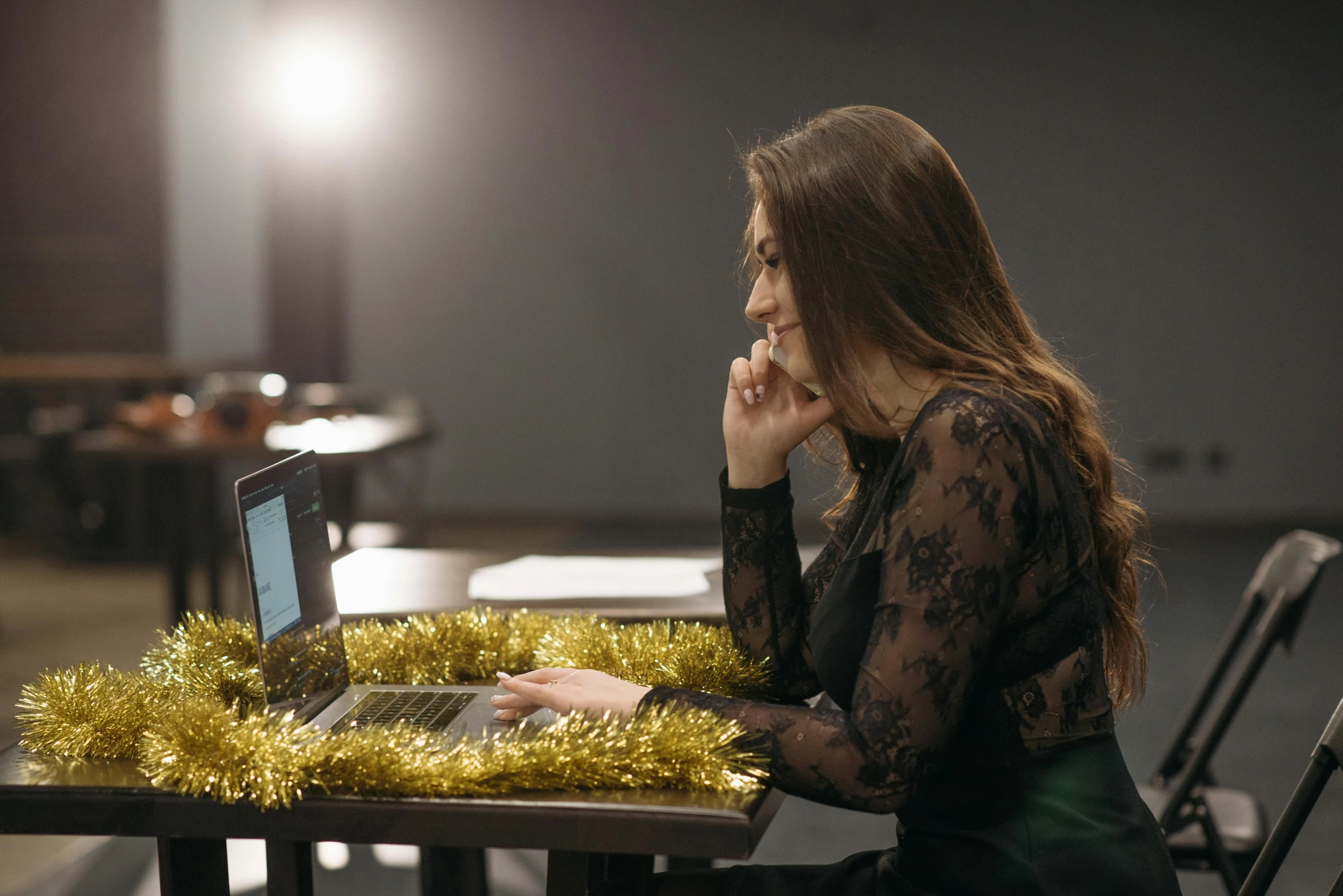 a woman sitting at a table with a laptop, wearing festive clothing, profile image, awkward, behind the scenes photo