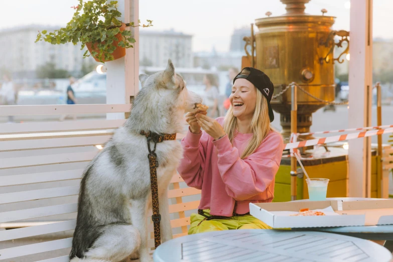 a woman sitting at a table with a dog, pexels contest winner, excited russians, eating outside, aurora aksnes, a blond