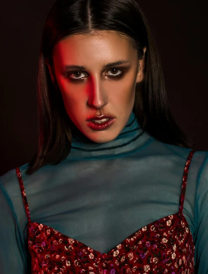 a woman in a red dress posing for a picture, an album cover, inspired by Elsa Bleda, trending on pexels, blue turtleneck, haunted expression, sexy face with full makeup, non binary model