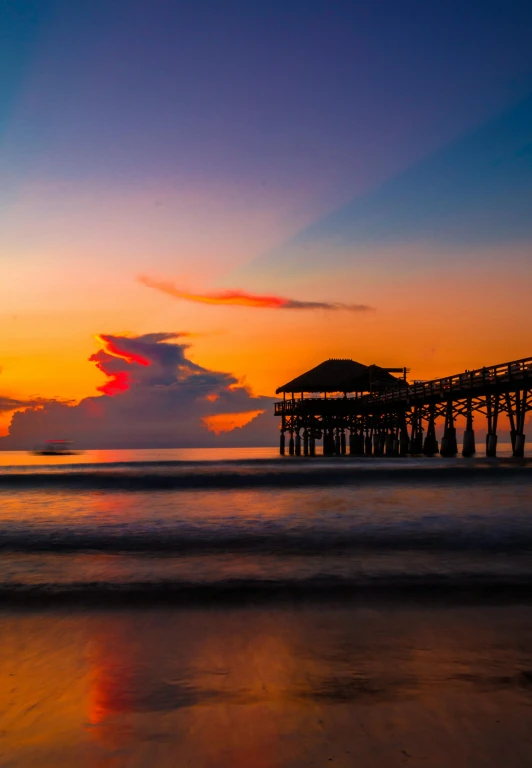 a pier sitting on top of a sandy beach, during a sunset, profile image, florida, suns