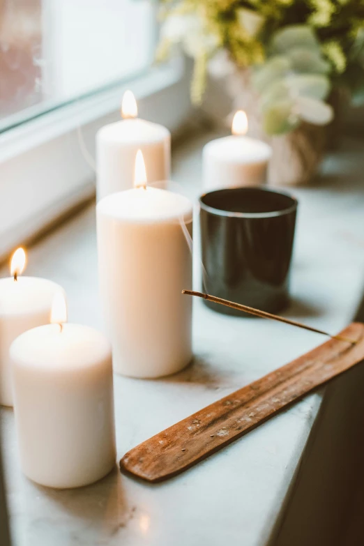 a group of white candles sitting on top of a window sill, a still life, trending on pexels, light and space, incense, profile image, vanilla