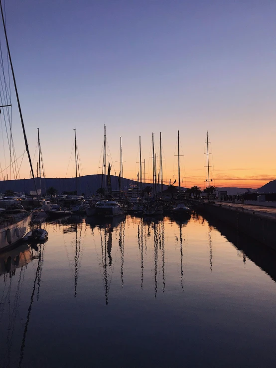 a number of boats in a body of water, a picture, pexels contest winner, reflections in copper, ((sunset)), three masts, photo on iphone