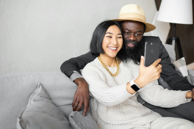 a man and woman sitting on a couch taking a selfie, black curly beard, hugging, high res photograph, half man half asian black bull