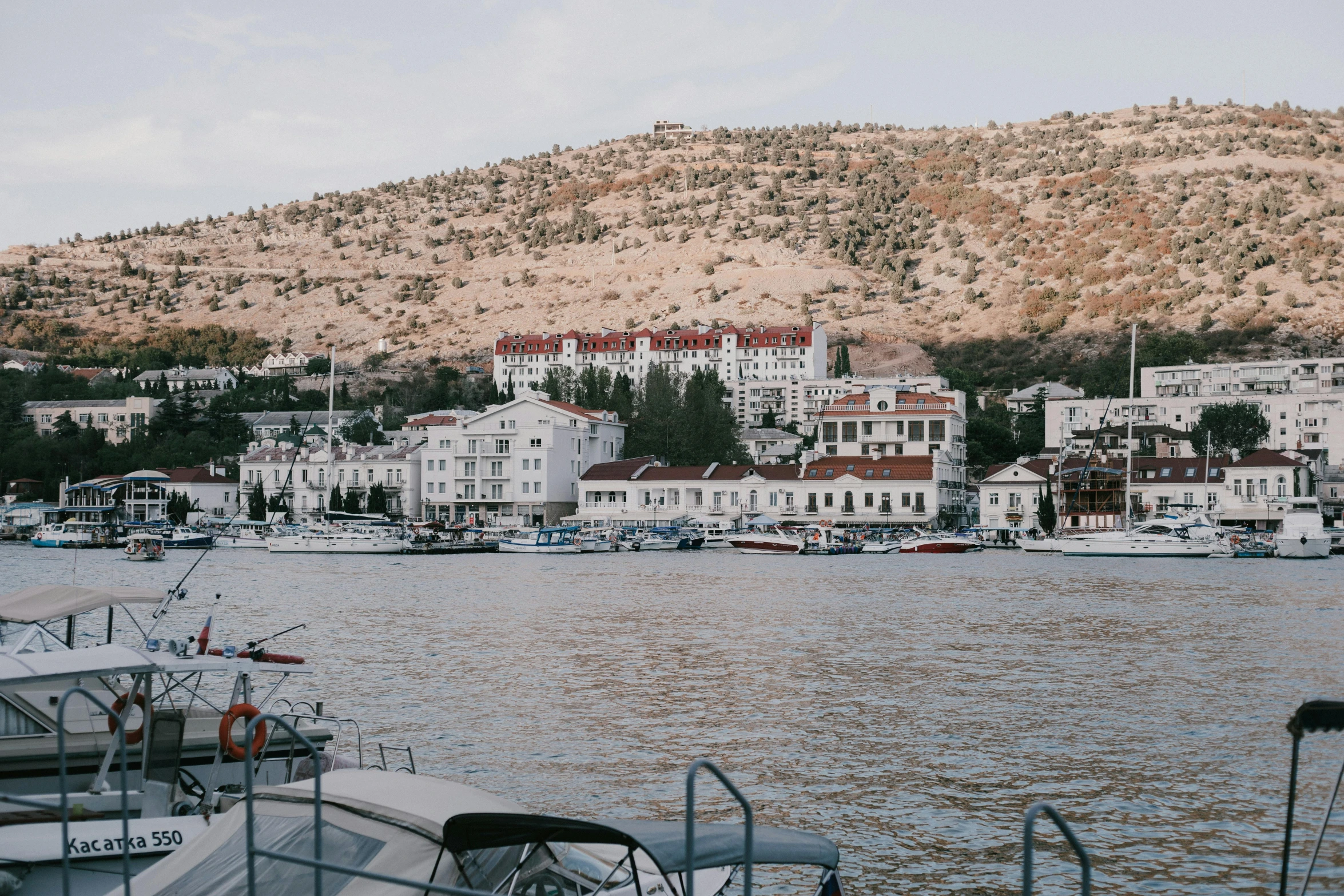 a large body of water filled with lots of boats, by Emma Andijewska, pexels contest winner, art nouveau, split near the left, hills in the background, trending on vsco, white buildings