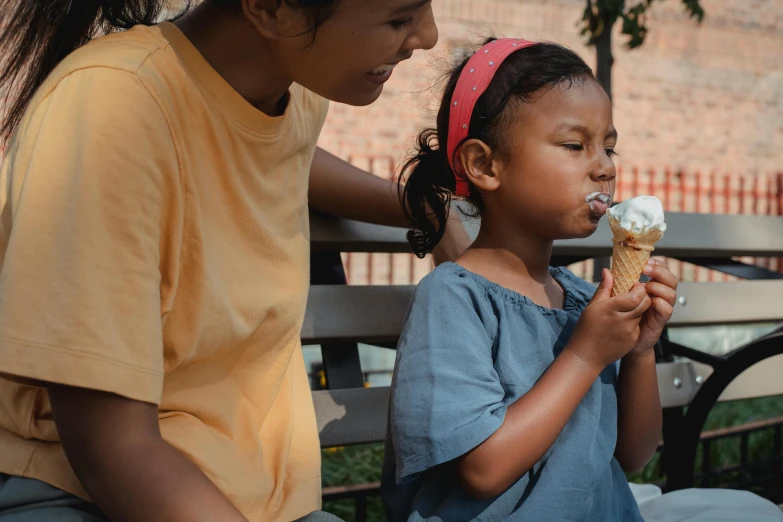 a woman sitting next to a little girl eating an ice cream cone, pexels contest winner, realism, diverse, 15081959 21121991 01012000 4k, thumbnail, indian girl with brown skin