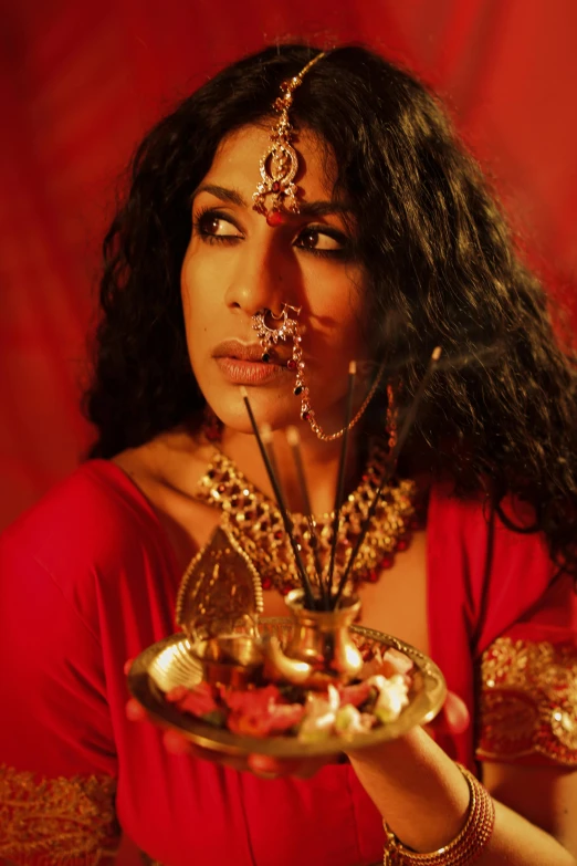 a woman in a red dress holding a plate, an album cover, inspired by Raja Ravi Varma, transgressive art, sza, close up shot of an amulet, cinematic and dramatic red light, dressed as an oracle