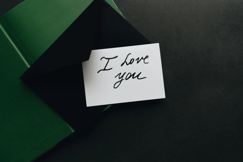 a piece of paper with the words i love you written on it, unsplash, green and black colors, presents, dark. no text, high quality photo
