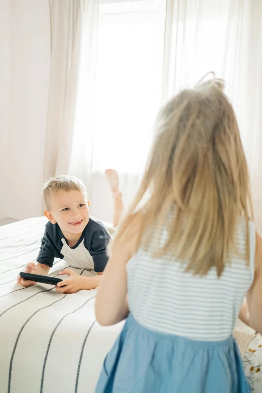 a little boy and a little girl sitting on a bed, pexels, happening, playing games, with his back turned, handheld, full product shot