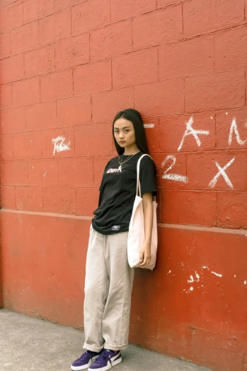 a woman leaning against a wall with graffiti on it, an album cover, trending on r/streetwear, asian women, black t-shirt, 33mm photo