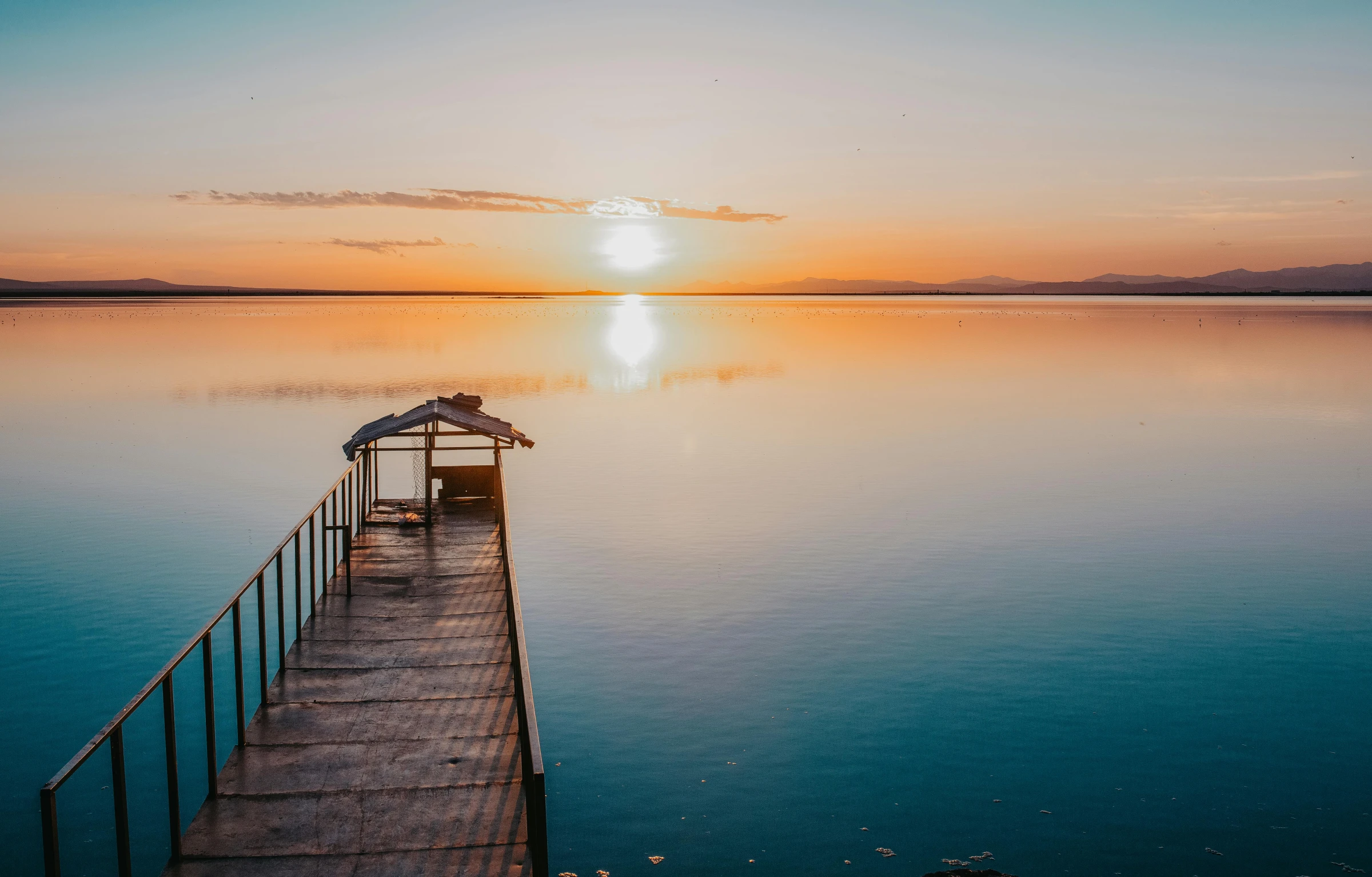 a dock in the middle of a large body of water, pexels contest winner, sunset light, fan favorite, the dead sea, lake blue