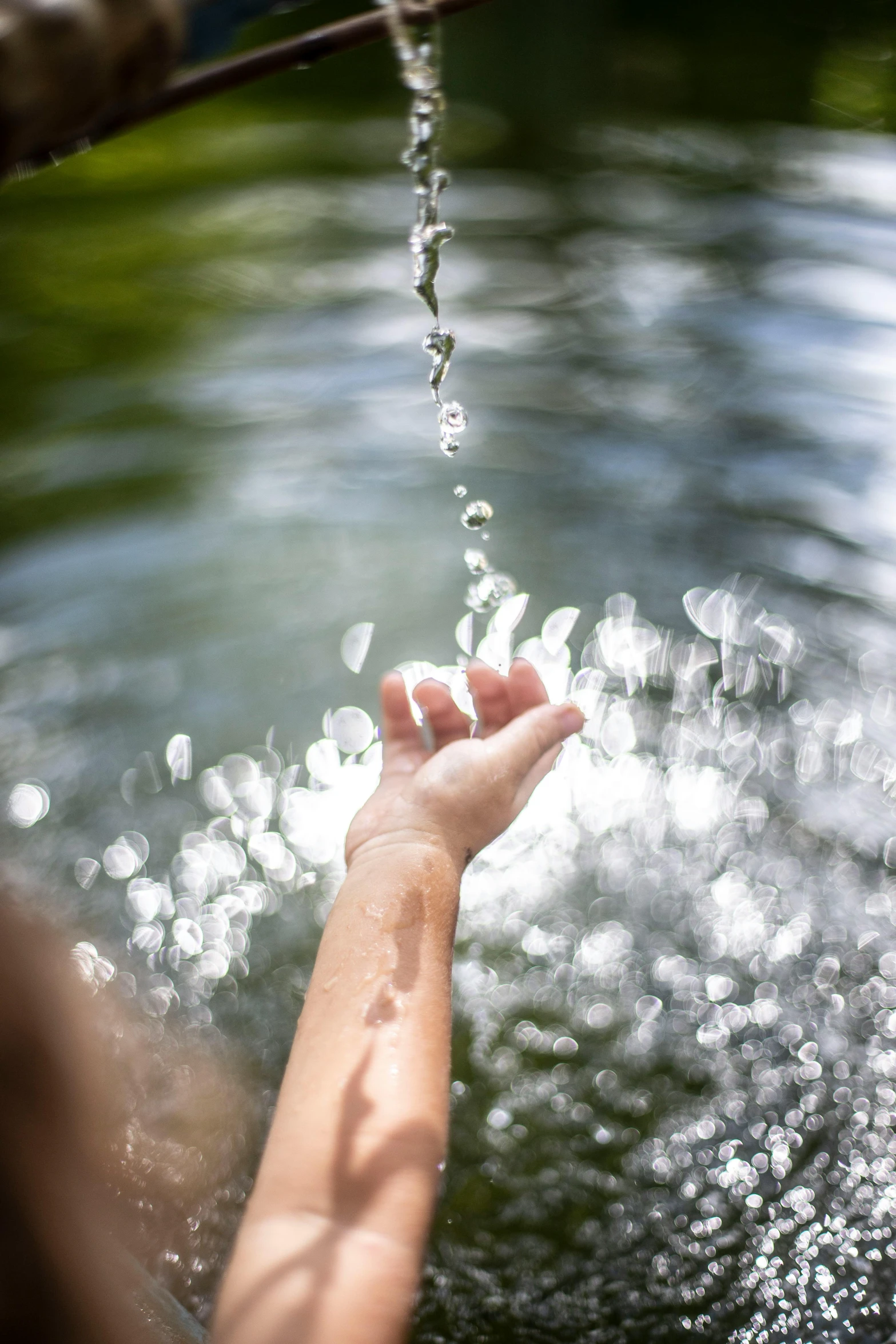 a person washing their hands in a body of water, bubbles in the air, summer sunlight, swirling, paddle of water