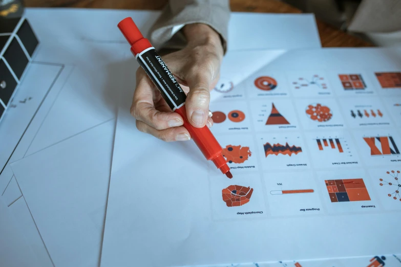 a person writing on a piece of paper with a red marker, by Adam Marczyński, pexels contest winner, analytical art, infographic with illustrations, red and orange color scheme, multiple stories, graph design