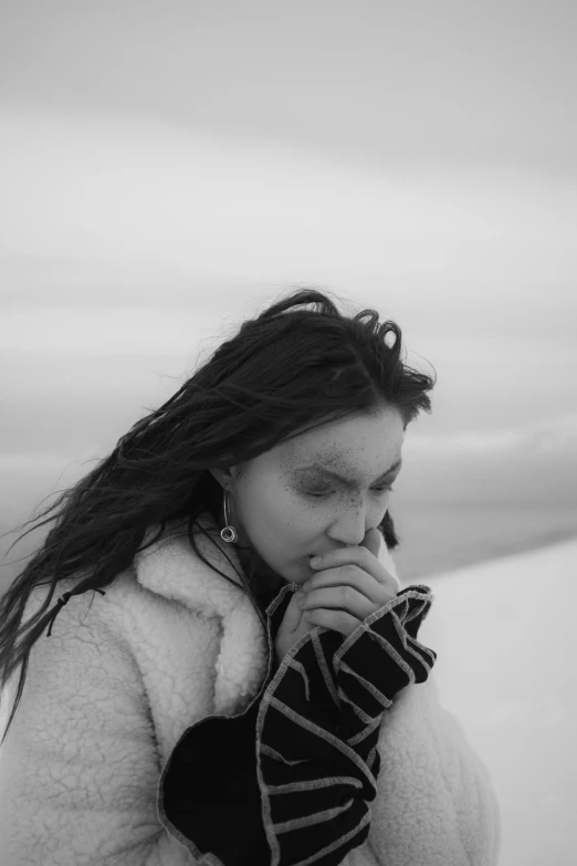 a woman standing on top of a snow covered slope, a black and white photo, trending on pexels, long windblown black hair, florence pugh, with tears, cl