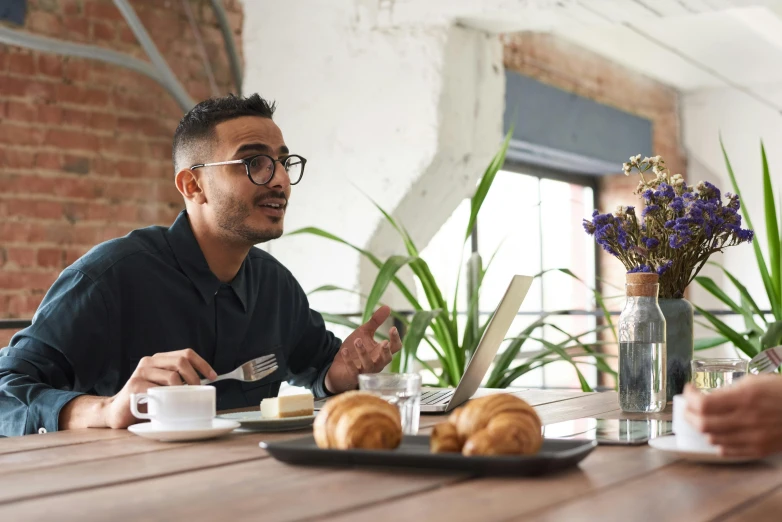 two men sitting at a table having a conversation, pexels contest winner, 9 9 designs, aboriginal australian hipster, with a laptop on his lap, having a snack