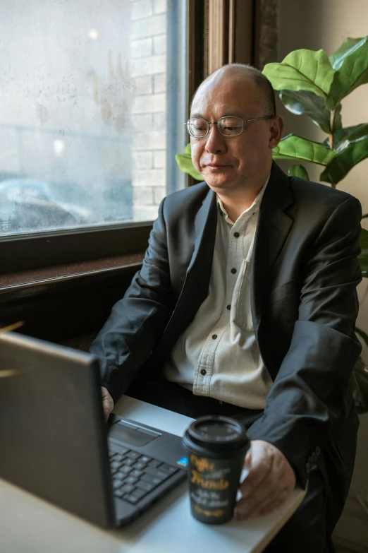 a man sitting in front of a laptop computer, a portrait, inspired by Fei Danxu, unsplash, wearing a suit and glasses, a man wearing a black jacket, photograph taken in 2 0 2 0, sitting down casually
