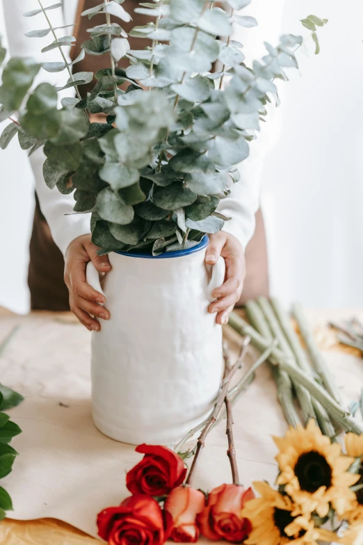 a woman holding a vase of flowers on a table, inspired by Hendrik Gerritsz Pot, trending on unsplash, arts and crafts movement, organic ceramic white, professional product photo, made of flowers and leaves, large tall