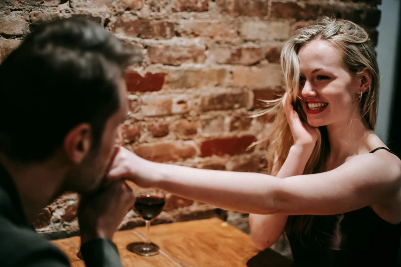 a man and a woman sitting at a table, by Lee Loughridge, pexels contest winner, flirting smiling, greeting hand on head, lachlan bailey, speakeasy