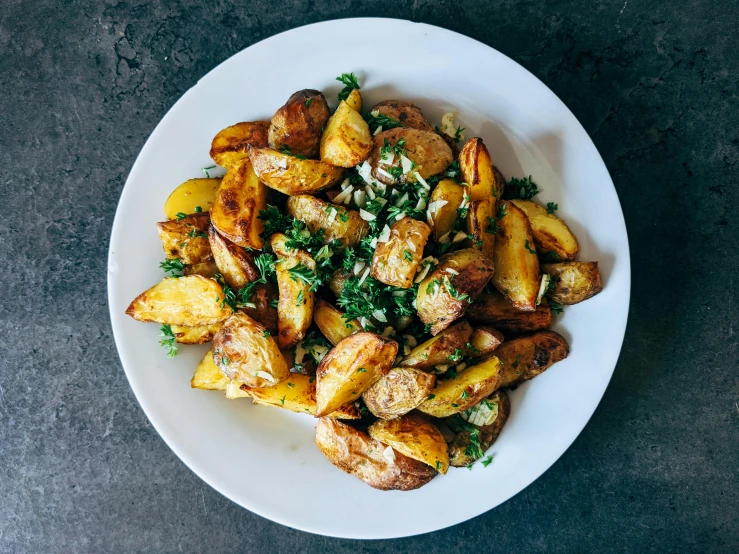 a white plate topped with potatoes and parsley, by Carey Morris, unsplash, fan favorite, salad, full body in shot, high - angle view