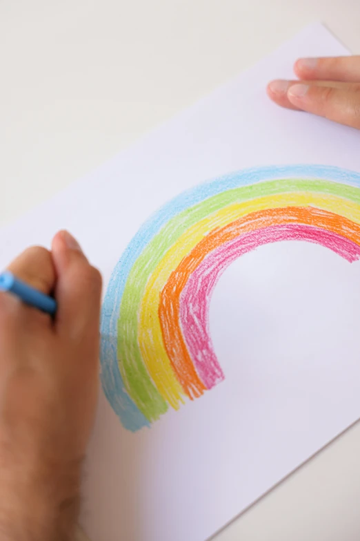 a person is drawing a rainbow on a piece of paper, a child's drawing, thumbnail, promotional image, opening shot, high resolution image