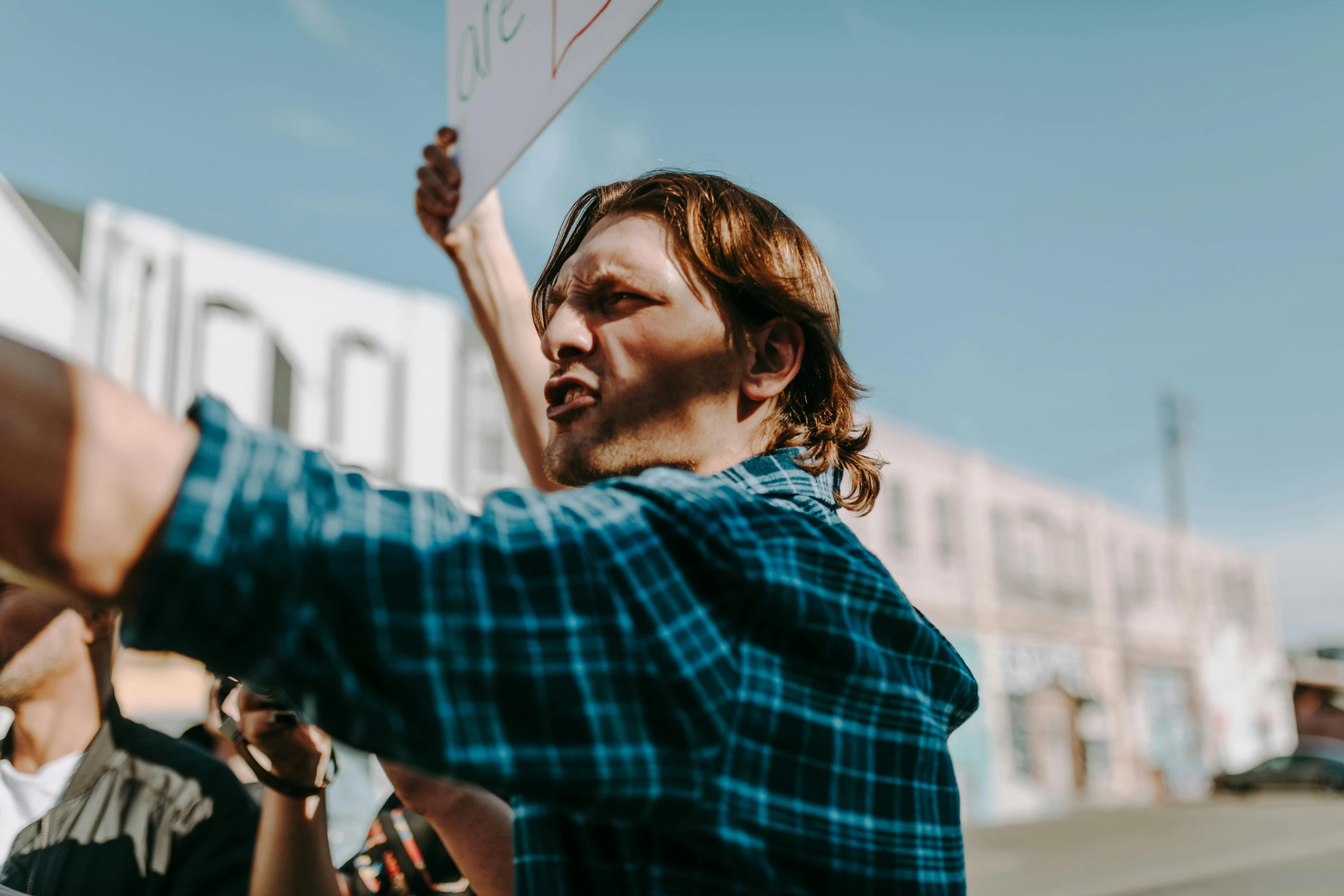 a man holding a sign in front of a building, trending on pexels, protest movement, avatar image, looking from shoulder, owen klatte