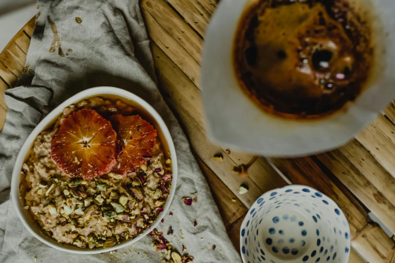 a bowl of oatmeal sitting on top of a wooden table, by Lee Loughridge, trending on unsplash, moroccan tea set, caramel, infused with a dream, thumbnail