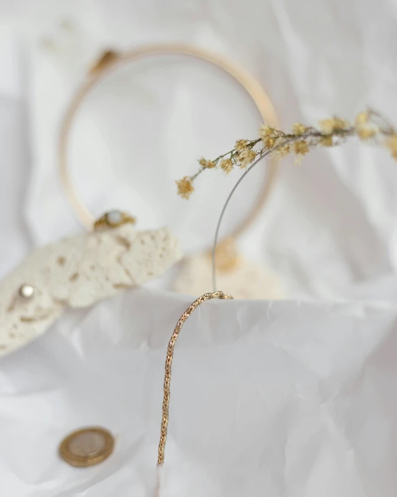 a pair of earrings sitting on top of a white sheet, by Helen Stevenson, unsplash, rococo, gold crown and filaments, detail shot, hairband, detailed product photo