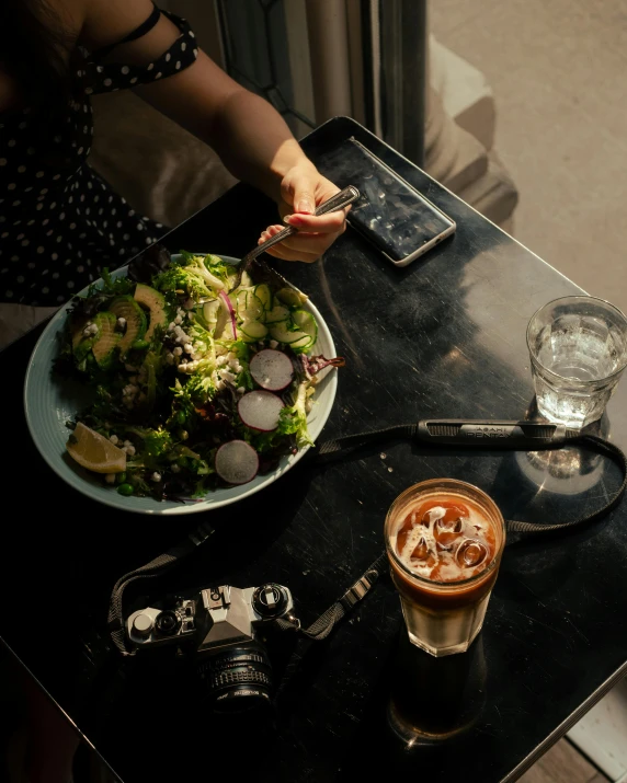 a woman sitting at a table with a plate of food, by Carey Morris, pexels contest winner, cold brew coffee ), salad, taking a picture, hasselblad photo