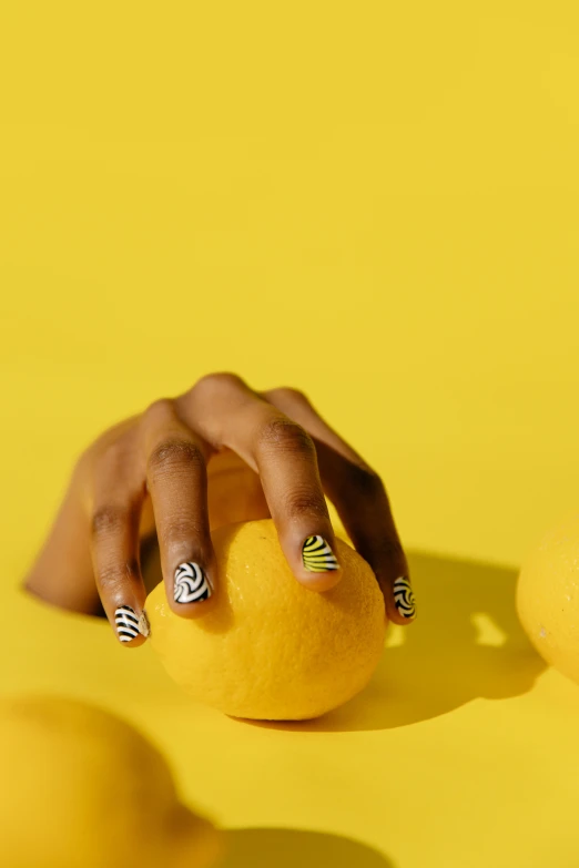a close up of a person holding a lemon, inspired by Man Ray, op art, neat nails, tiger stripes, maria borges, product shoot