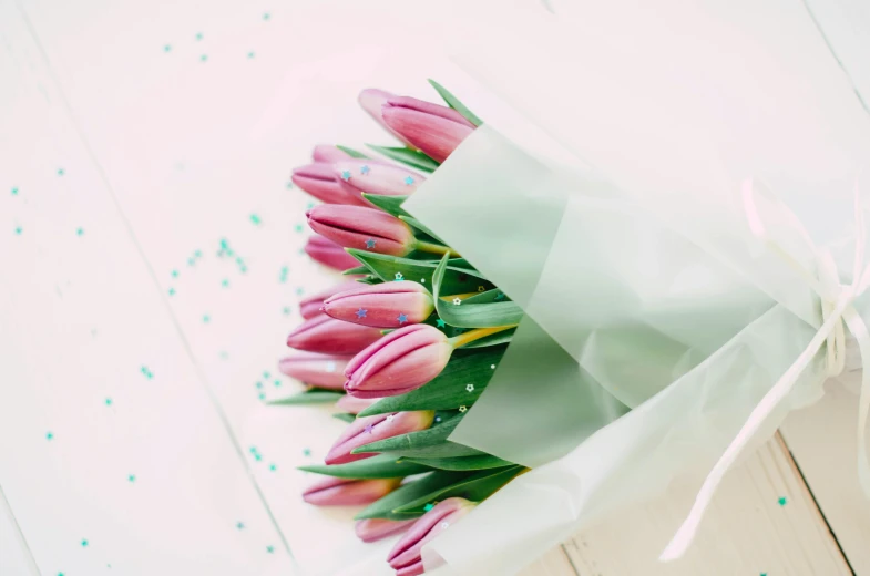 a bouquet of pink tulips on a white table, by Sylvia Wishart, trending on unsplash, purple and green, retro stylised, high quality paper, glossy surface