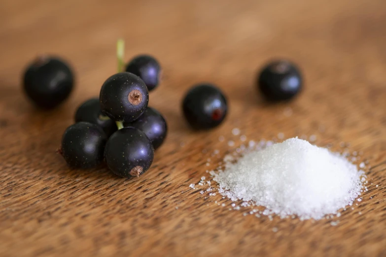 a pile of blackberries sitting on top of a wooden table, by Sylvia Wishart, unsplash, covered in salt, ingredients on the table, cherries, miniature product photo