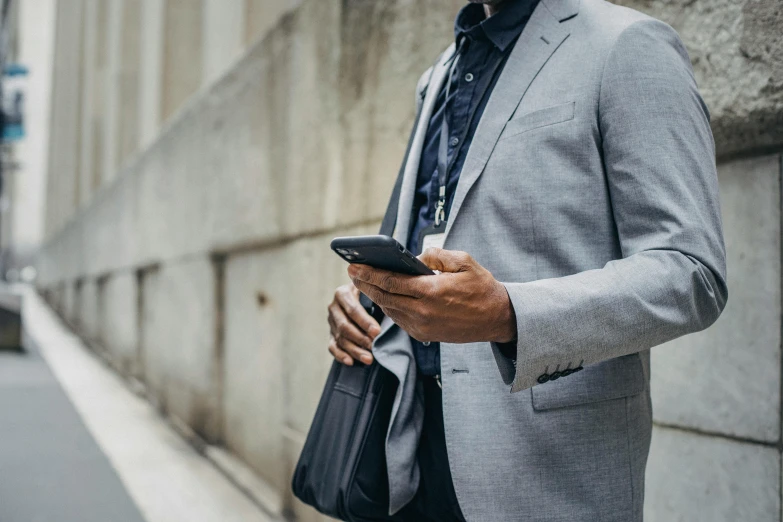 a man in a suit holding a cell phone, trending on pexels, grey jacket, 1 4 5 0, multiple stories, dressed casually