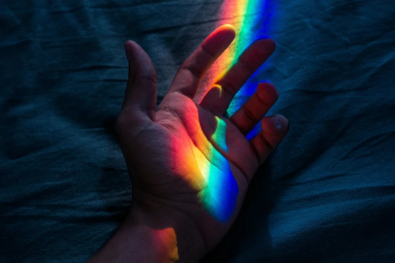 a person's hand with a rainbow painted on it, trending on pexels, holography, glowing light and shadow, alessio albi, prideful, instagram post