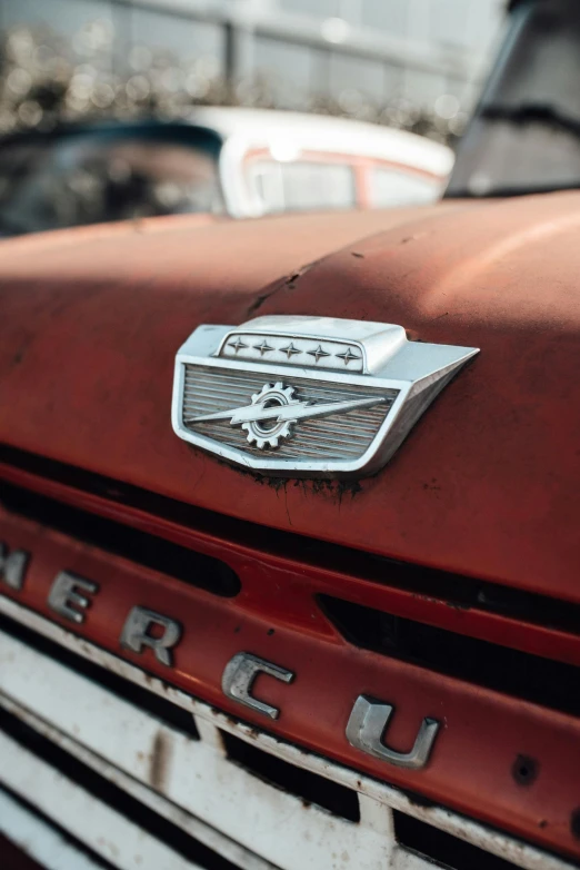 an old red truck is parked in a lot, an album cover, by Peter Churcher, trending on pexels, sharp metal crest, mercury, made from mechanical parts, emblem