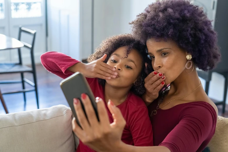 a woman and a little girl sitting on a couch, pexels contest winner, happening, hold up smartphone, hand over mouth, african american young woman, maroon