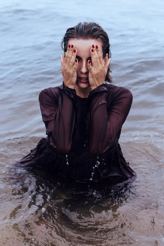 a woman with her hands on her face in the water, an album cover, pexels contest winner, wearing dark maritime clothing, instagram photo, wet fabric, taken in the late 2010s